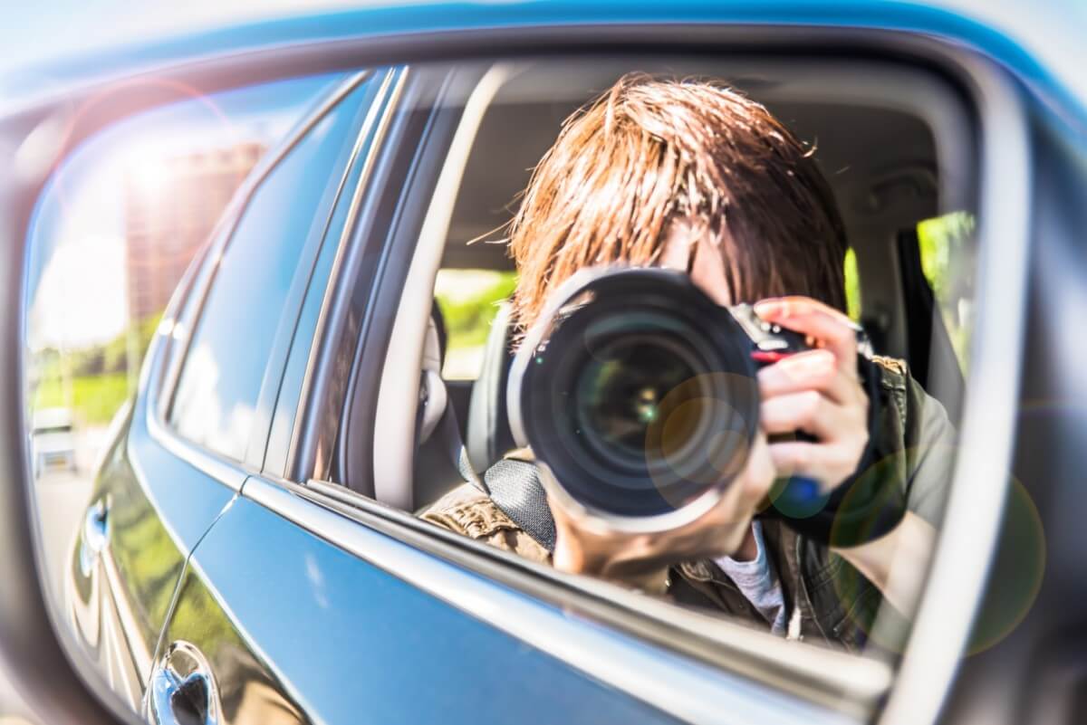 車の中からカメラで浮気の証拠をとっている探偵