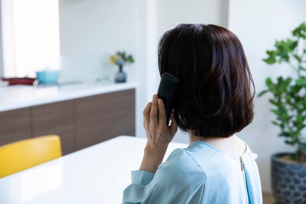 浮気調査依頼で電話をしている女性