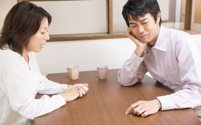 深刻な顔で話をする夫婦
